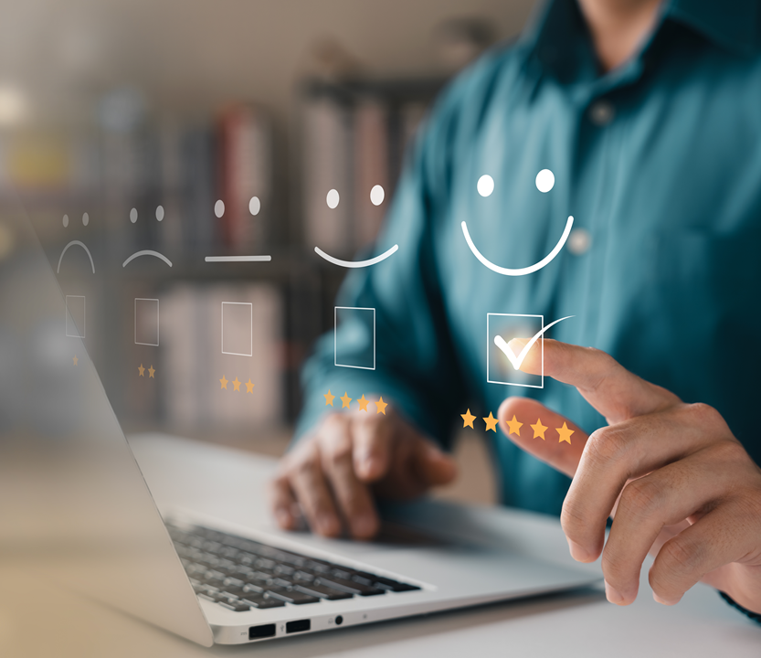 Symbolbild für Kundenzufriedenheit: Hand am Laptop gibt digitale Fünf-Sterne-Bewertung mit Smiley ab